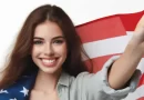 Jovem sorridente veste bandeira dos EUA, simbolizando o sonho americano.