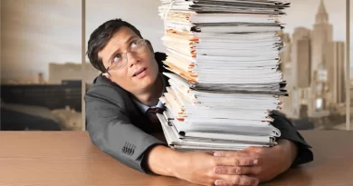 Homem sobrecarregado com pilha de documentos, simbolizando a exploração no trabalho moderno.