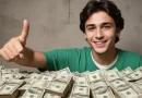 Jovem comemora a conquista do primeiro milhão, com mesa repleta de dinheiro.